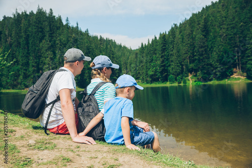 family sitting at beach of mountains lake