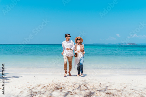 Young happy muslim couple white dress on running seashore. Travel Vacation Retirement Lifestyle Concept. young couple running together on the beach in vacation day. summer time.