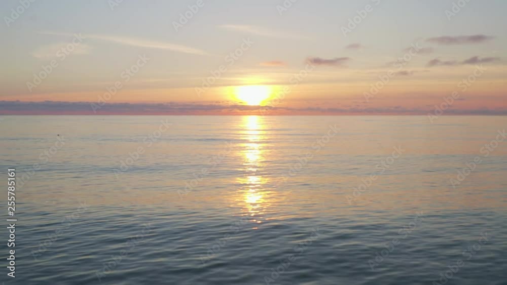 Golden sun in evening sky and smooth sea surface from above flying drone. Aerial view evening sundown in golden sky and sea on colorful horizon Golden sun in evening sky and smooth sea surface from above flying drone. Aerial view evening sundown in golden sky and sea on colorful horizon