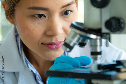 Close up scientist looking through a microscope in a laboratory. Science technology research and development concept
