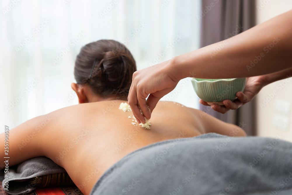 Obraz premium Asian woman enjoying a salt scrub massage at spa.