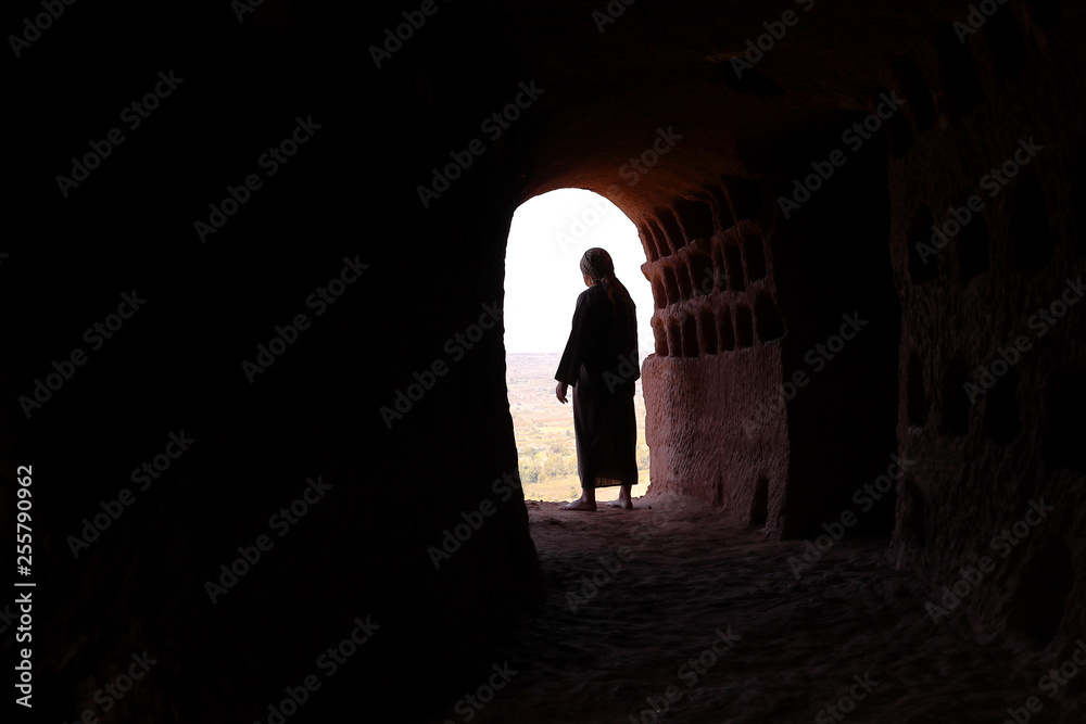 MAN WITH ROBE AND PALESTINIAN SCARF AT THE ENTRANCE OF A CAVE