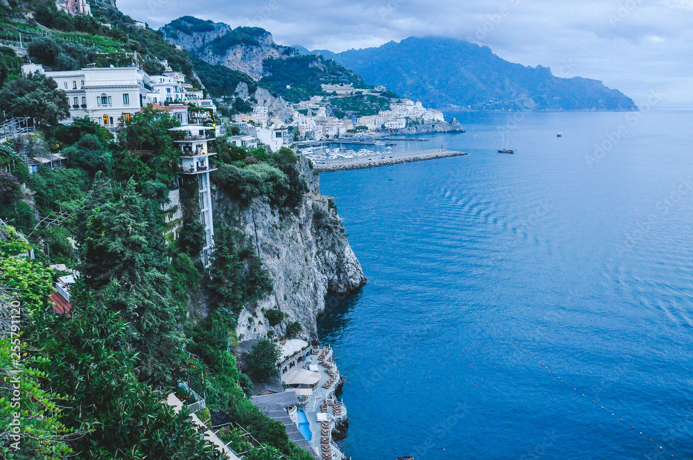 Buildings overlooking the cliff, with the city of Amalfi in the background