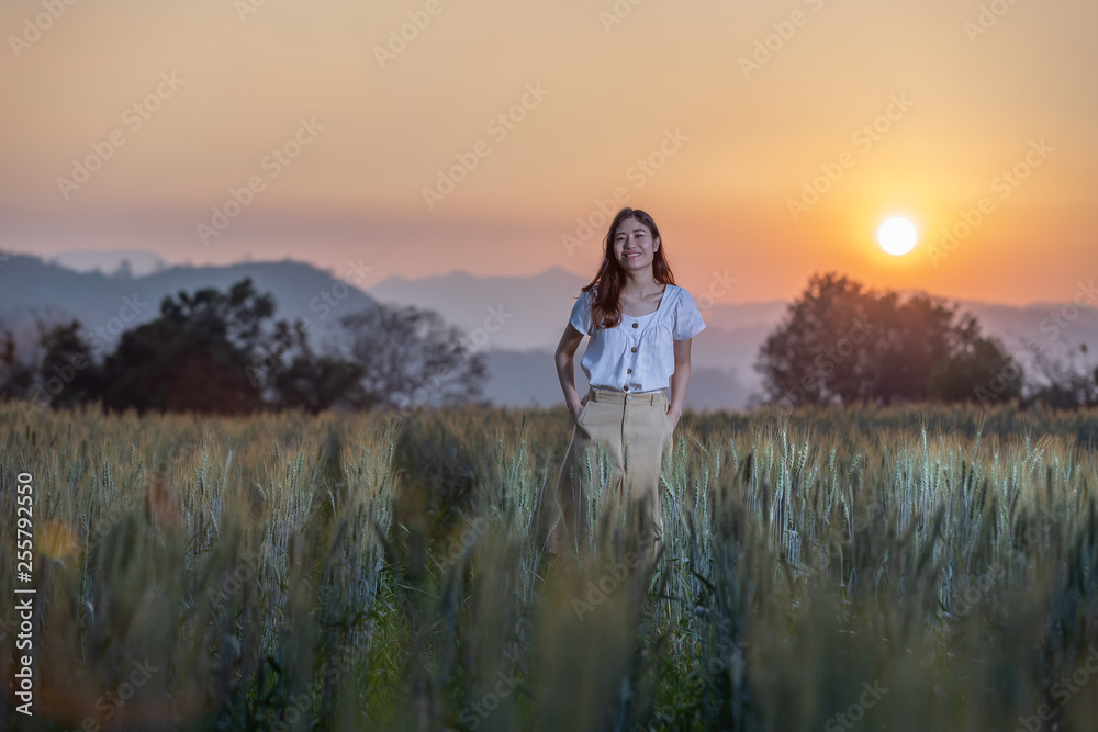 Beautiful asian woman having fun at barley field in summer at sunset time