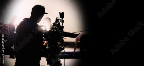 Behind video camera in film or movie production on tripod and professional gear which shooting in location or studio with crew team and prop or set and ready to online live broadcast or tv on air