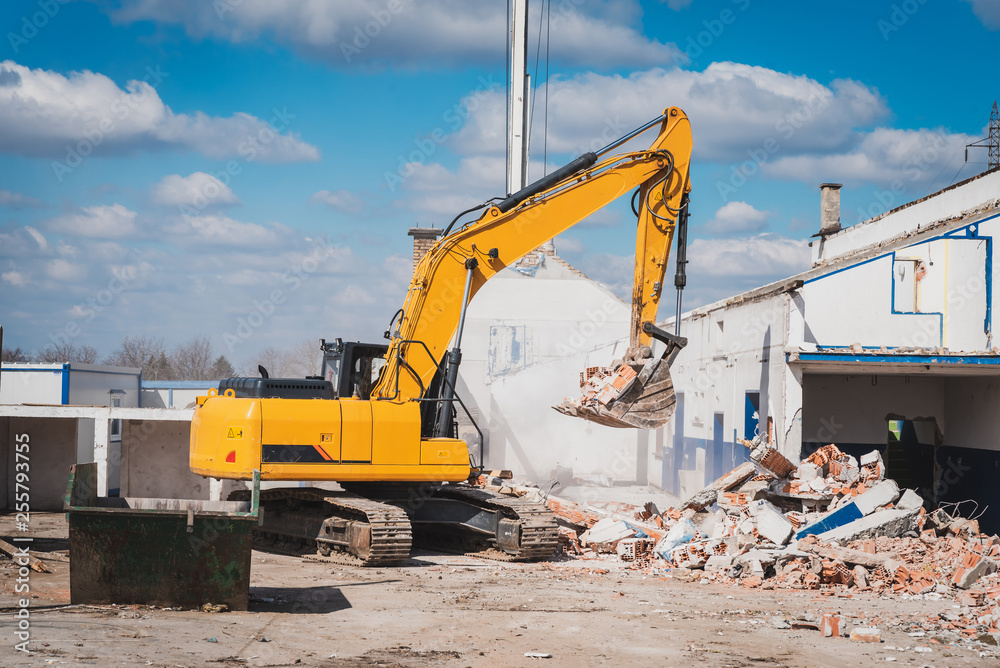 large construction machines are knocking down the houses on the construction site