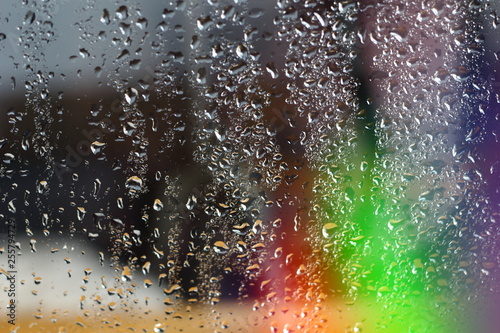 Abstract blurred colorfull rainbow background aurora borealis on window glass with raindrops with multicolored lights with free copy space for text