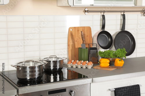 Set of clean cookware, utensils and products on table in modern kitchen