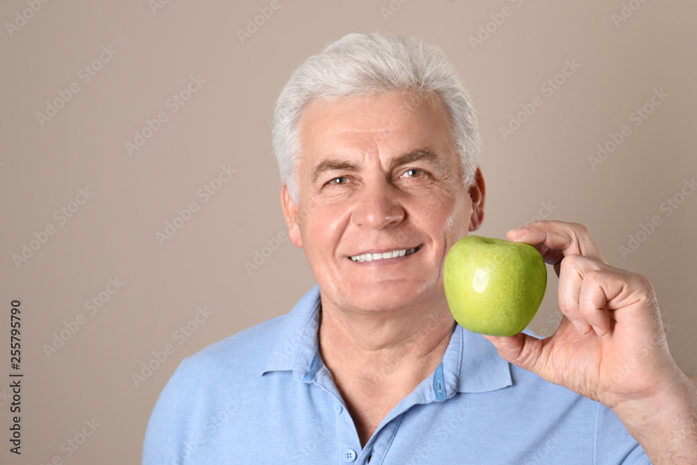 Mature man with healthy teeth and apple on color background Mature man with healthy teeth and apple on color background