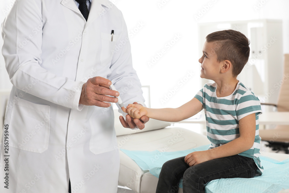 Obraz premium Little patient and doctor with lancet pen in hospital. Diabetes control