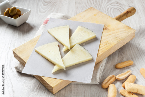 Manchego cheese on wooden board with olives photo