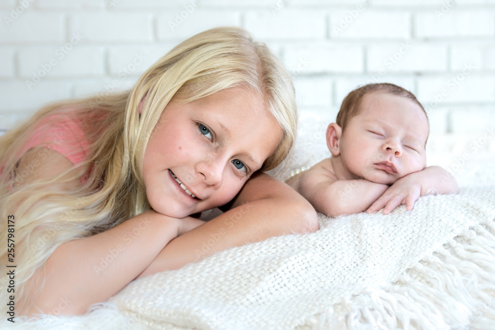 Infant and older sisters both heads on arms pose together Infant and older sisters both heads on arms pose together
