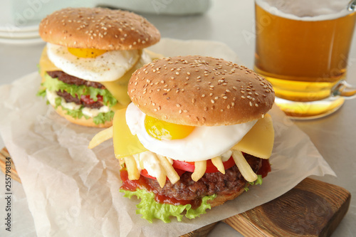 Tasty burgers with fried egg on wooden board