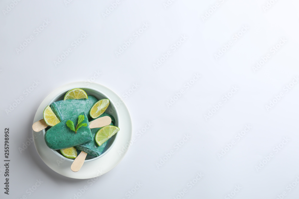 Bowl with delicious spirulina popsicles and lime slices on white background, top view Bowl with delicious spirulina popsicles and lime slices on white background, top view