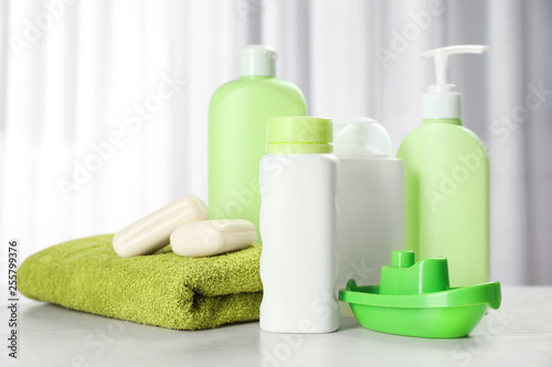 Baby cosmetic products, toy and towel on table indoors