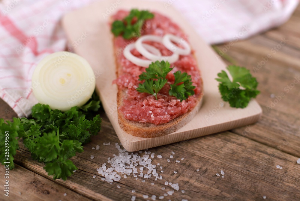 slice of bread with minced meat, parsley and onions - on rustic wooden table - breakfast bread - pork mett slice of bread with minced meat, parsley and onions - on rustic wooden table - breakfast bread - pork mett