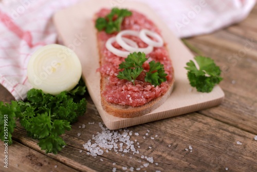 slice of bread with minced meat, parsley and onions - on rustic wooden table - breakfast bread - pork mett