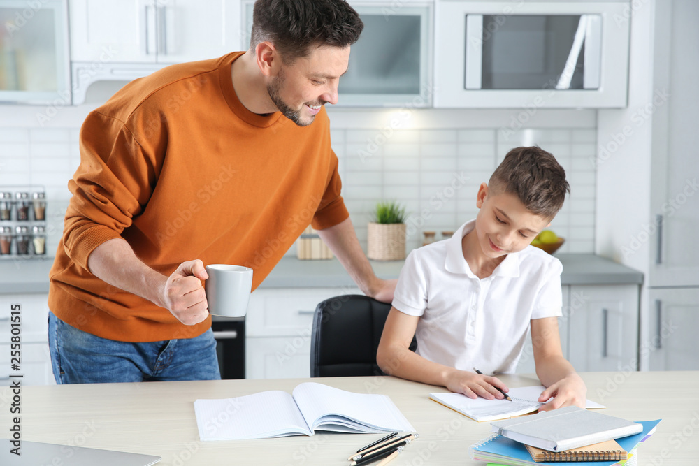Dad helping his son with homework in kitchen Dad helping his son with homework in kitchen