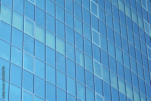 New office building in business center. Wall made of steel and glass with blue sky. 