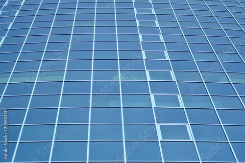 New office building in business center. Wall made of steel and glass with blue sky. 