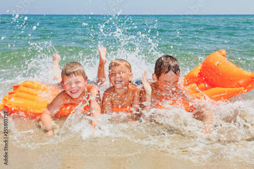 Three kids having fun splashing water on a beach photo