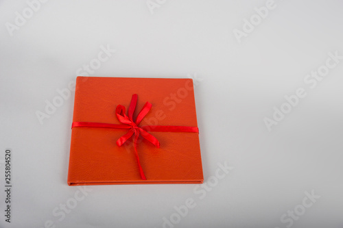Fototapeta Naklejka Na Ścianę i Meble -  Red book with red ribbon. Red gift on a wooden background