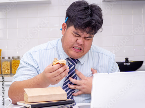 Fat Asian man felling heart pain while he eating food.Man with chest pain suffering from heart attack.