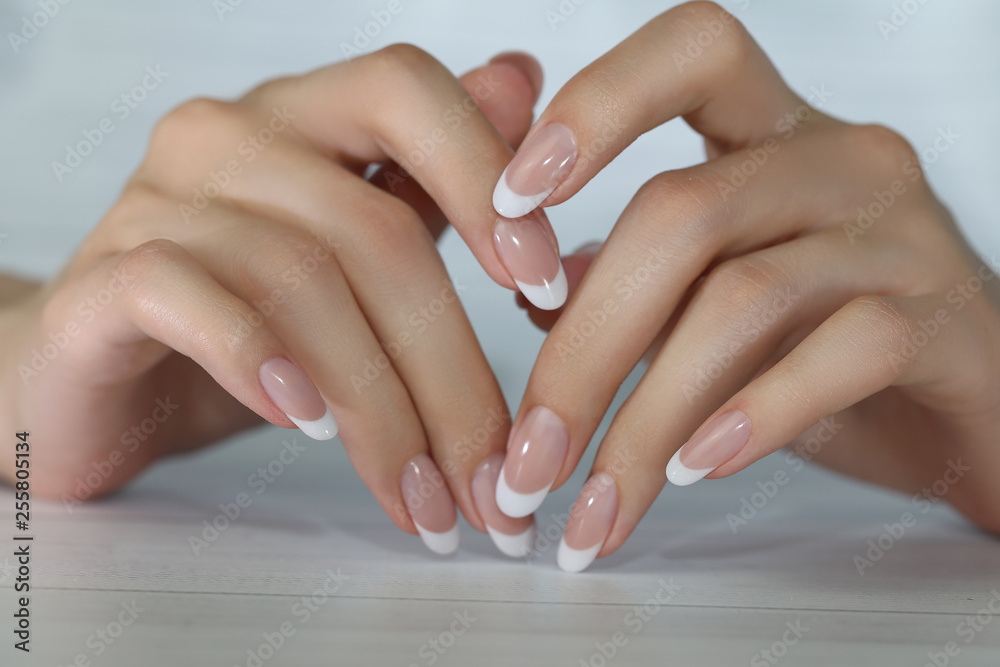 beautiful female hands with long nails light white manicure and a bottle of  nail polish Stock Photo - Alamy