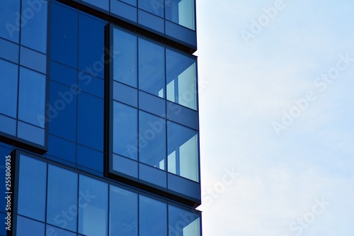 New office building in business center. Wall made of steel and glass with blue sky. 