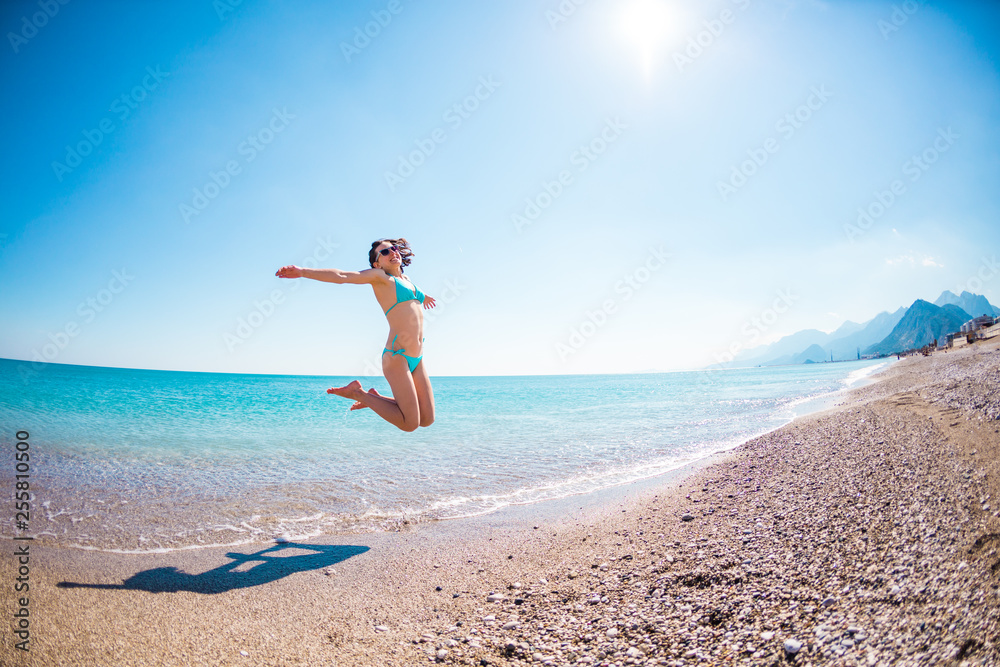 Girl in a bathing suit jumping on the beach.