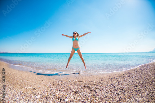 Girl in a bathing suit jumping on the beach.