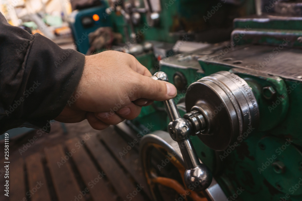 The hand of the machine operator creates a mechanical switch on the lathe. The hand of the machine operator creates a mechanical switch on the lathe.
