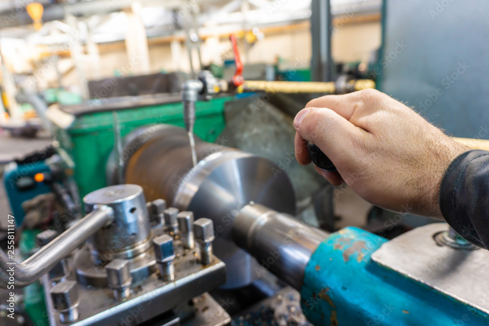 The hand of the machine operator creates a mechanical switch on the lathe.