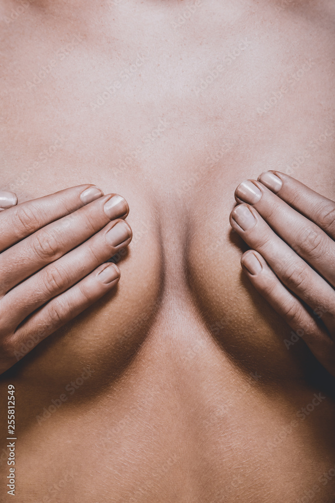 Woman breast covered by hands. Plastic surgery concept. Stock Photo