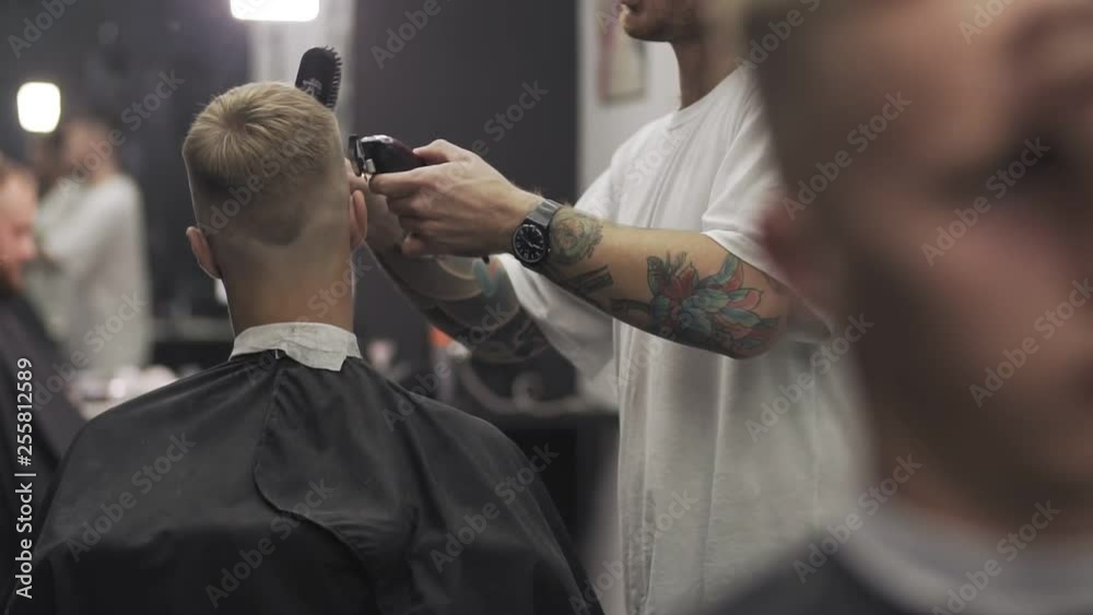 Barber cutting hair with hair clipper. Male haircut with electric razor. Styling with electric trimmer. Man hairdressing with electric shaver Barber cutting hair with hair clipper. Male haircut with electric razor. Styling with electric trimmer. Man hairdressing with electric shaver