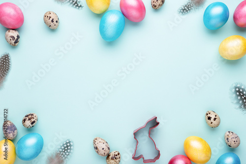 Frame made of colorful Easter eggs on turquoise background. Top view, copy spase, minimal styled.