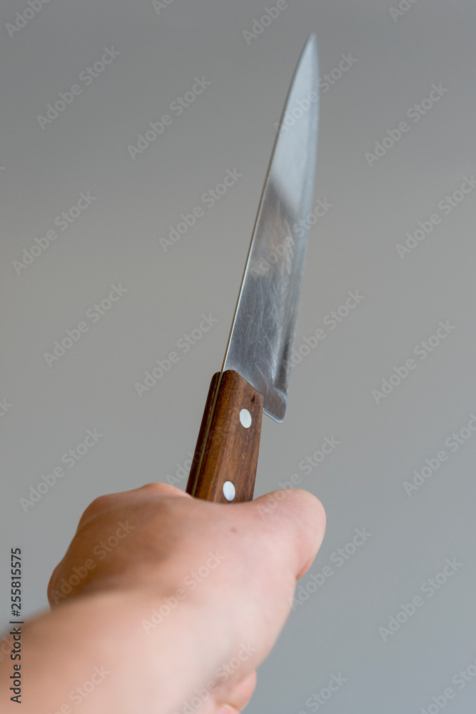 Fotografie Man's hand with a knife on gray background