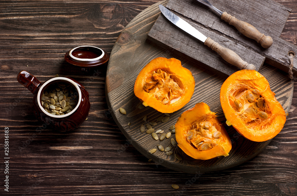 Sliced pumpkins and pumpkin seeds in ceramic pot on a wooden tray. Close-up of cooking process. Autumn, vegetarian dish Sliced pumpkins and pumpkin seeds in ceramic pot on a wooden tray. Close-up of cooking process. Autumn, vegetarian dish