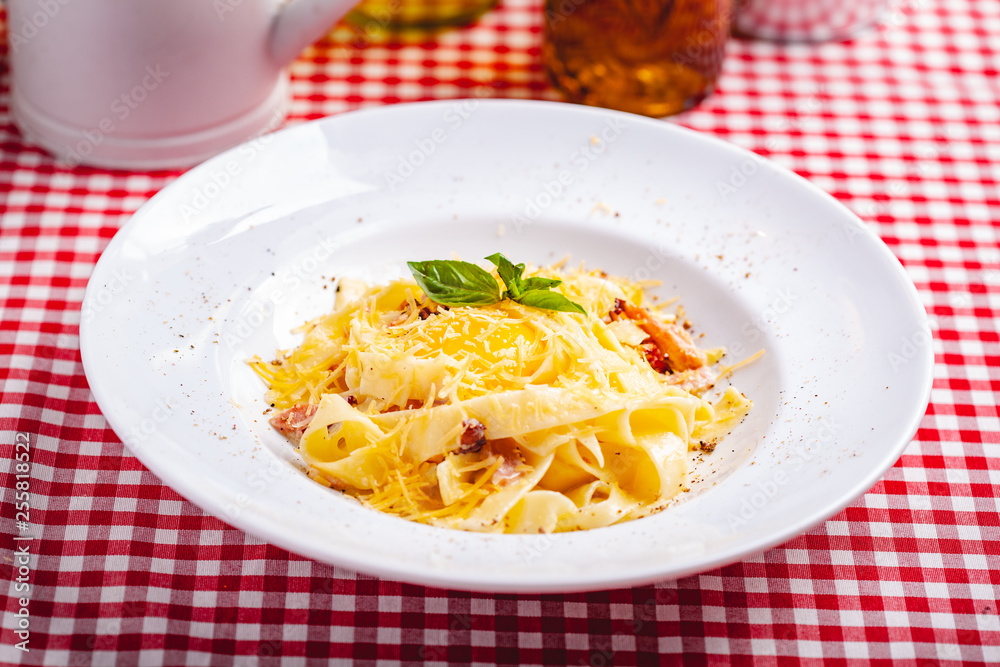 Italian cuisine. Pasta carbonara with bacon, cheese and egg on white plate. Close up