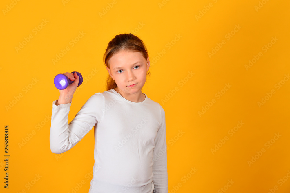 The girl is engaged in fitness with dumbbells, on a yellow background The girl is engaged in fitness with dumbbells, on a yellow background