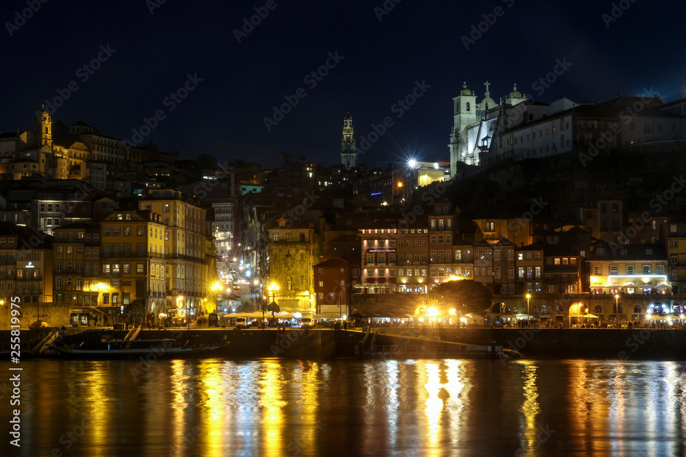 night panorama of city centre skyline of porto, portugal with Clérigos Tower in centre and light reflections on douro river