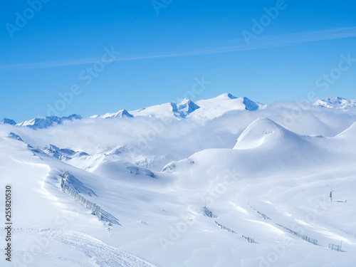 Winter landscape with snow covered slopes and blue sky, view from the top of Kitzsteinhorn mountain on . Kaprun ski resort, National Park Hohe Tauern, Austrian Alps, Europe.