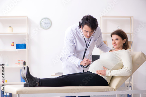 Wallpaper Mural Old pregnant woman visiting young male doctor  Torontodigital.ca
