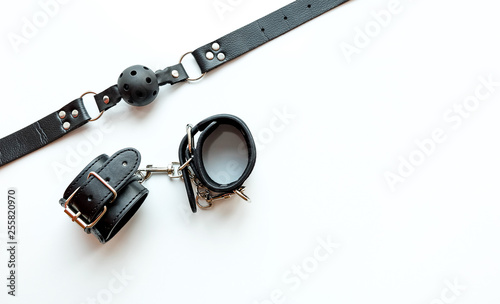 BDSM leather sex attributes: handcuffs, leather belt, ball gag
