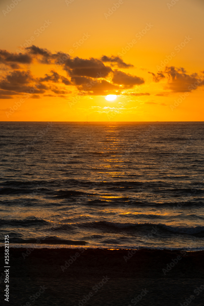 A golden sunrise with reflection on the Atlantic Ocean on Delray Beach, Florida.