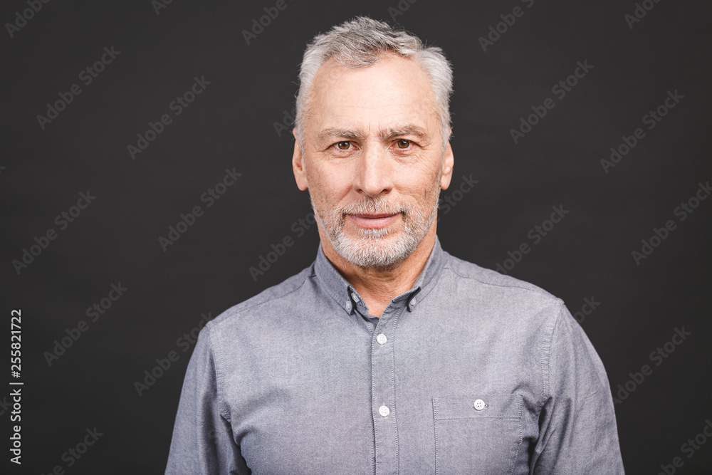 Portrait of a mature serious businessman isolated against black background. Happy senior man looking at camera with copy space. Close up face of happy successful business man. Portrait of a mature serious businessman isolated against black background. Happy senior man looking at camera with copy space. Close up face of happy successful business man.