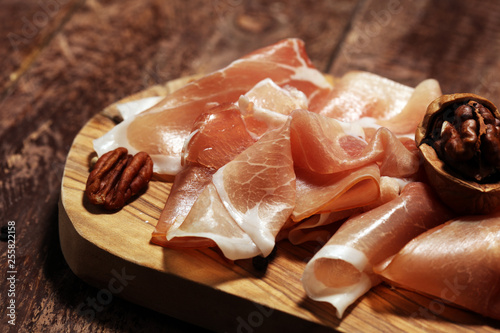 Italian prosciutto crudo or jamon with rosemary. Raw ham on rustic background photo