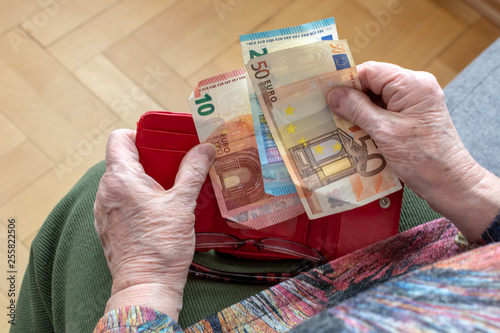 Hands of an elderly pensioner holding leather wallet with euro currency money. Concept of financial security in old age. photo