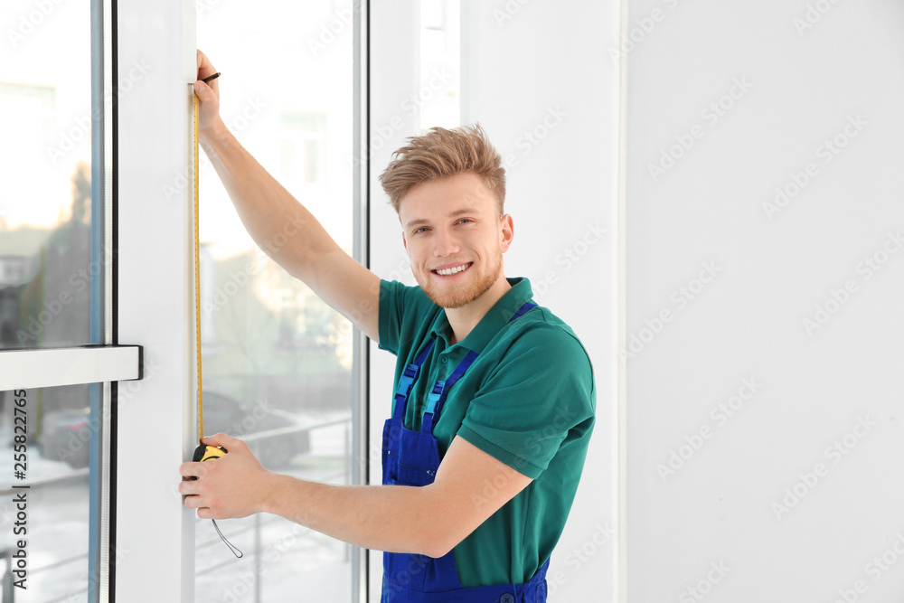 Service man measuring window for installation indoors