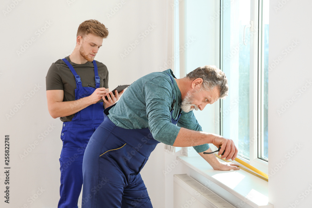 Obraz premium Service men measuring window for installation indoors